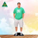 Man wearing a green t-shirt and gray shorts standing on a black mat with a colorful gradient background.