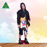 Cardboard cutout of a person wearing a colorful outfit with anime design on a gradient background.
