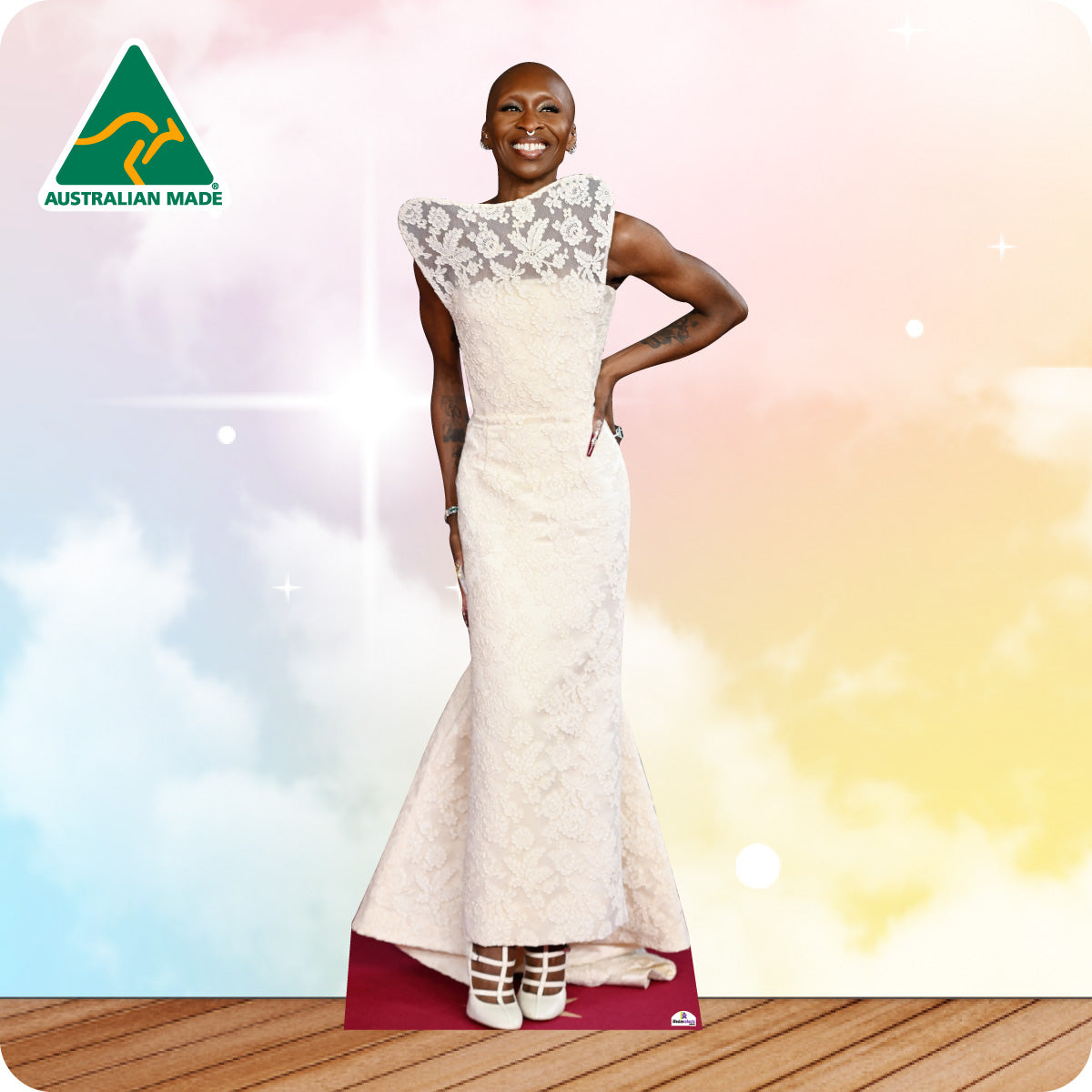 Woman wearing a white dress with lace details, standing on a wooden floor with a colorful background.