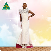 Woman wearing a white dress with lace details, standing on a wooden floor with a colorful background.