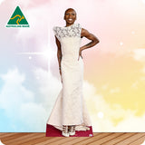 Woman wearing a white dress with lace details, standing on a wooden floor with a colorful background.