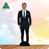 Man in a black suit standing on a wooden floor with a colorful gradient background.