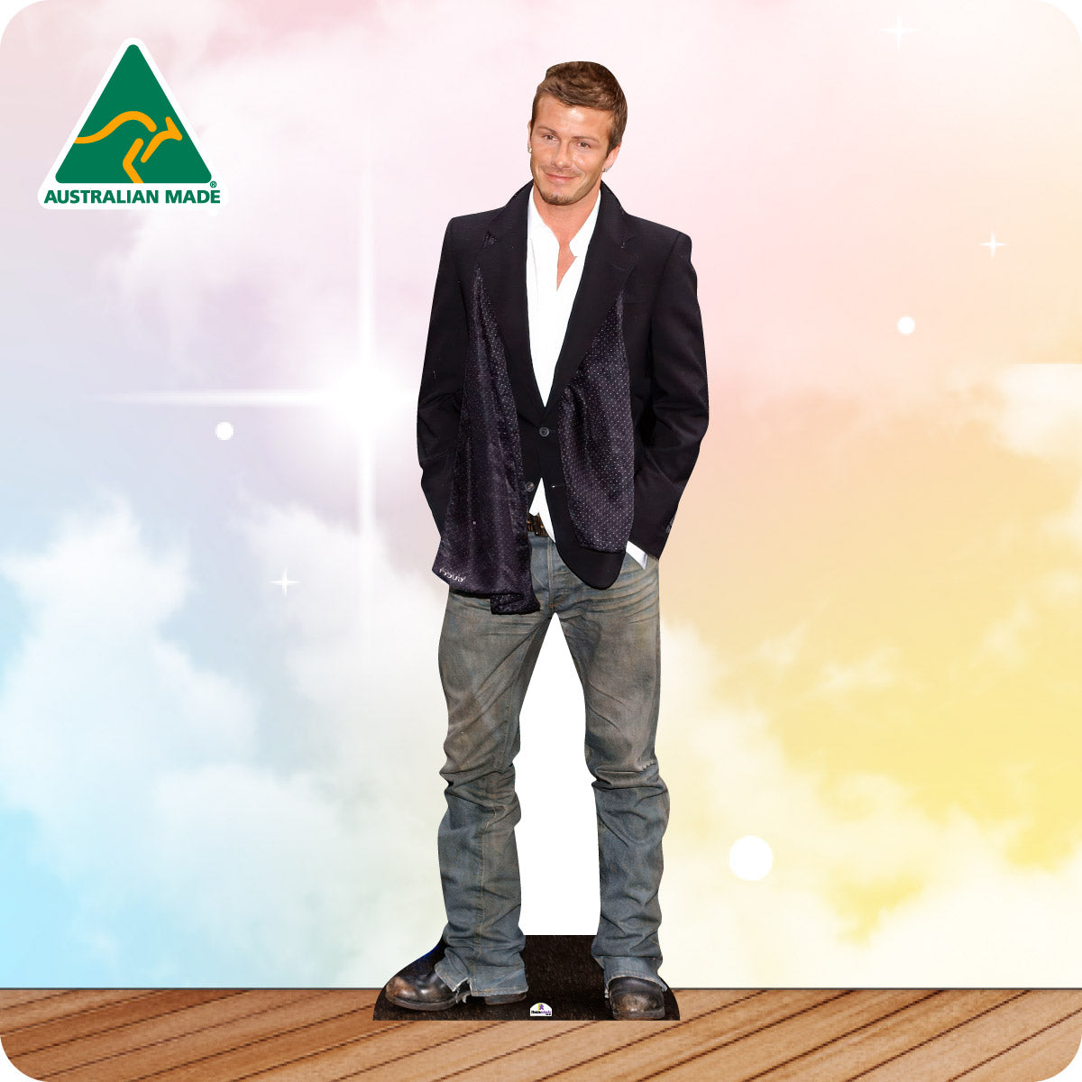 Man wearing a dark blazer and jeans standing on a wooden deck with a colorful background and 'Australian Made' logo.