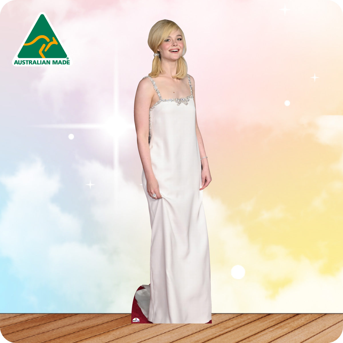 Woman in a white evening gown standing on a wooden floor with a colorful background, Australian Made logo visible.