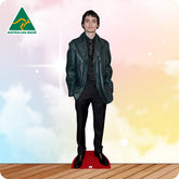 Cardboard standee of a person wearing a green jacket on a wooden floor with a colorful gradient background.