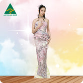 Woman in a floral dress standing on a wooden floor with a colorful, blurred background