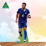 A die-cut cardboard cutout of soccer player Kylian Mbappé in a France national team blue jersey and shorts, standing on a grass patch with a soccer ball at his feet. The cutout is set against a pastel sky background with a wooden floor, featuring an 'Australian Made' logo in the top-left corner.