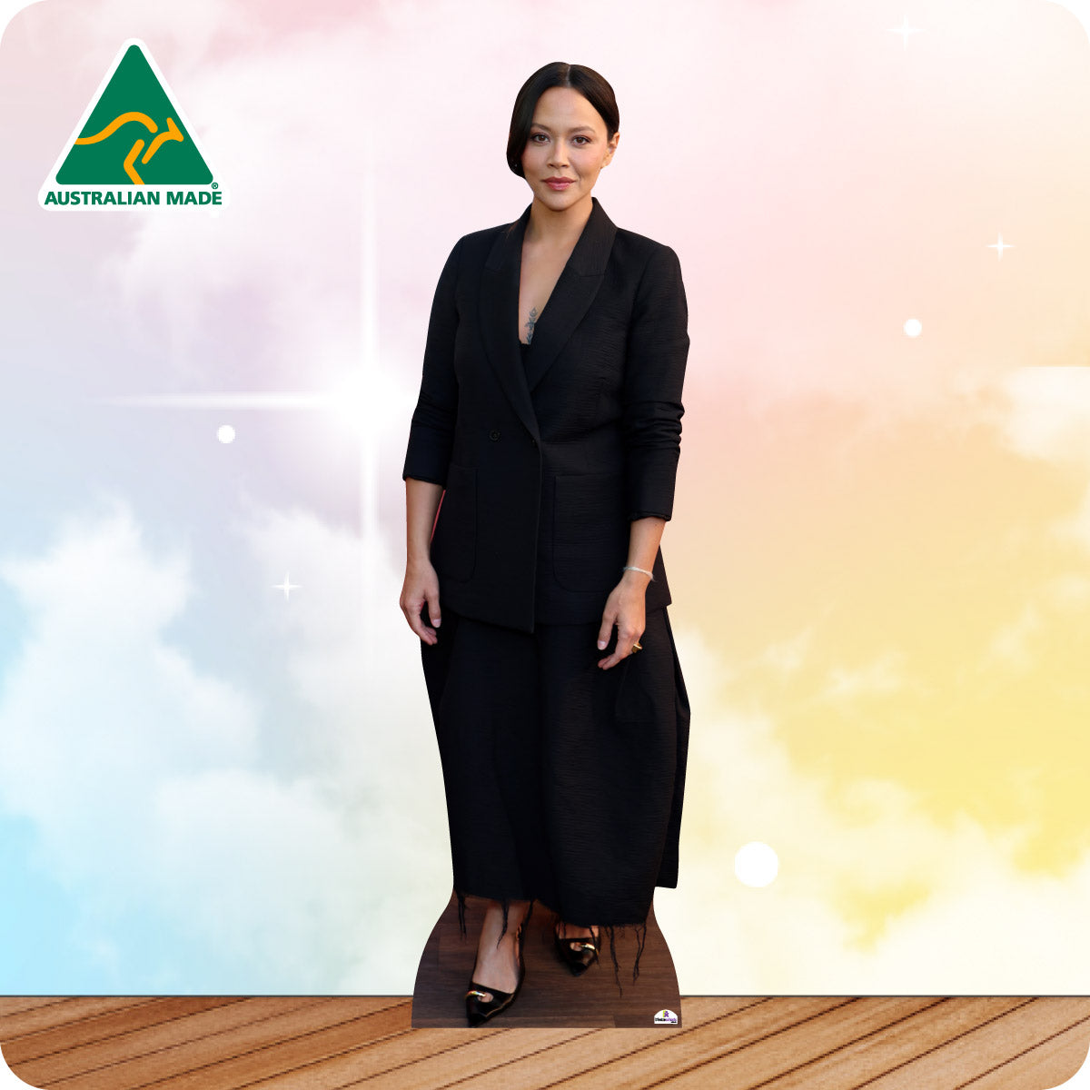 Woman in a black suit standing on a wooden floor with a colorful gradient background and Australian Made logo.