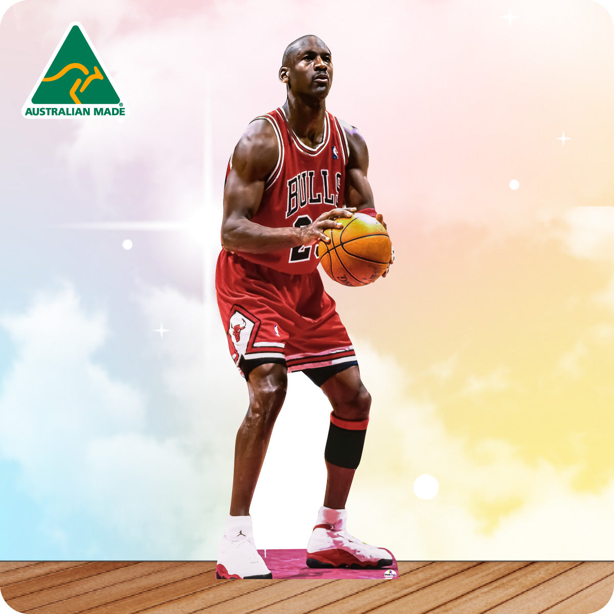 Basketball player in a red jersey holding a basketball on a wooden floor with a colorful background and Australian Made logo.