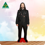 A full-body cardboard cutout of a smiling man with long dark hair wearing a black patterned suit and black shoes, standing on a red carpet over a wood floor. The background is a pastel sky with clouds and stars, with an 'AUSTRALIAN MADE' logo in the top-left corner.