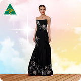 Woman wearing a black strapless gown with floral embroidery on a colorful background, with 'Australian Made' logo.