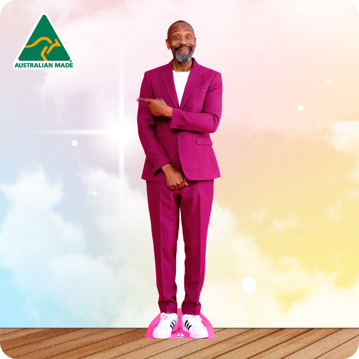Man in a pink suit standing on a wooden floor with a colorful background and 'Australian Made' logo.