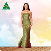 Woman in a gold strapless gown standing on a wooden floor with a colorful background