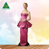 Woman in a pink evening gown standing on a wooden floor with a blurred background