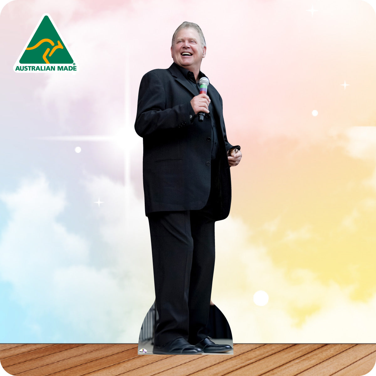 Man in a suit holding a microphone with 'Australian Made' logo on a colorful background