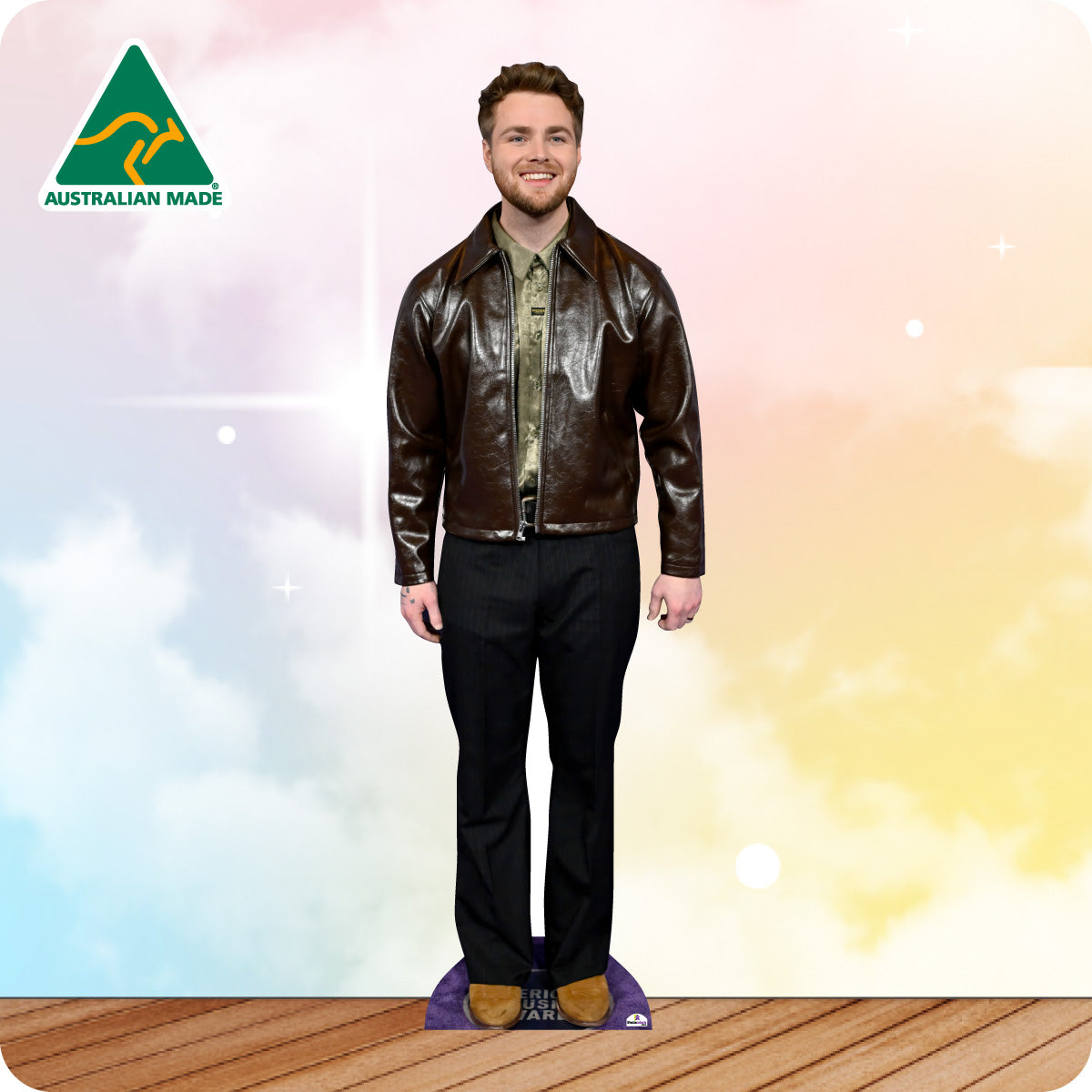 Man wearing a brown leather jacket and black pants on a wooden floor with a colorful gradient background.