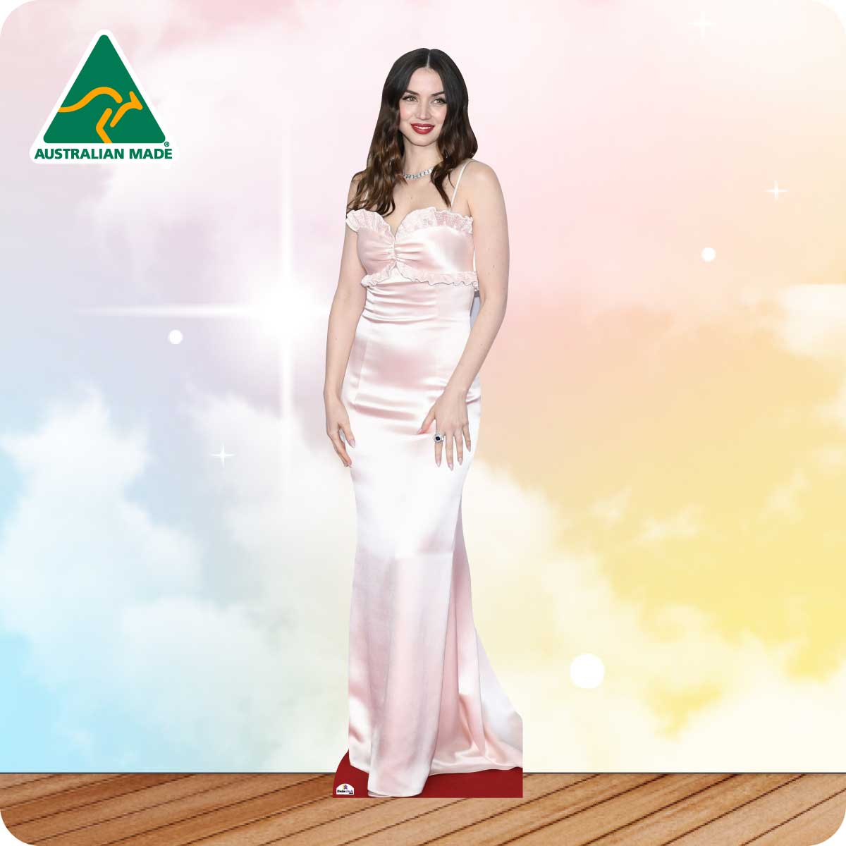 Woman in a pink gown standing on a wooden floor with a colorful, cloud-like background and 'Australian Made' logo.