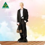 A full-body cardboard cutout standee of a young man with short blond hair, wearing a black suit, white shirt, and black belt, holding a zebra-print handbag. The standee is set against a pastel sky background with clouds and a wooden floor, with an 'AUSTRALIAN MADE' logo in the top-left corner.