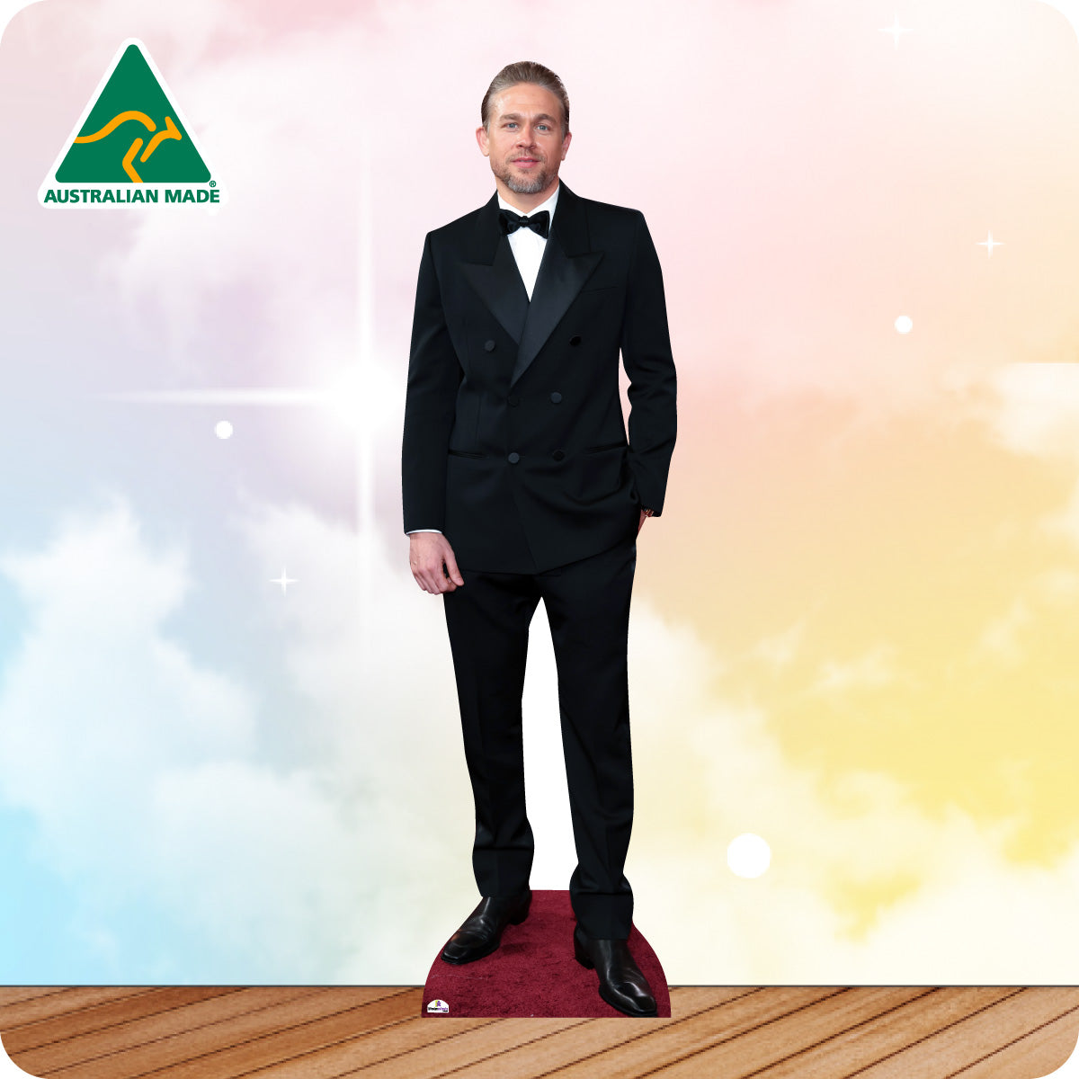 Man in a black suit standing on a red carpet with a colorful background and 'Australian Made' logo.