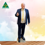 Cardboard cutout of a man in a suit with a yellow tie, standing on a wooden floor with a colorful background.