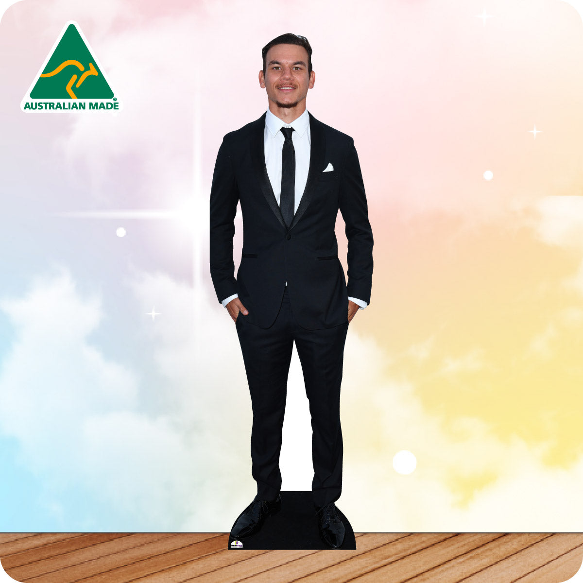 Man in a black suit standing on a wooden floor with a colorful gradient background.