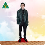 Cardboard standee of a person wearing a green jacket on a wooden floor with a colorful gradient background.