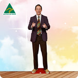 Cardboard cutout of a man in a suit with a colorful tie on a wooden floor and multicolored background.