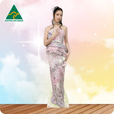 Woman in a floral dress standing on a wooden floor with a colorful, blurred background