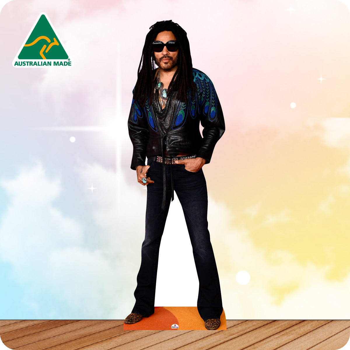 Cardboard cutout of a person wearing a leather jacket and sunglasses on a wooden floor with a colorful background.