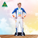 Cardboard cutout of a Formula 1 driver in a colorful racing suit with visible branding on a wooden floor.