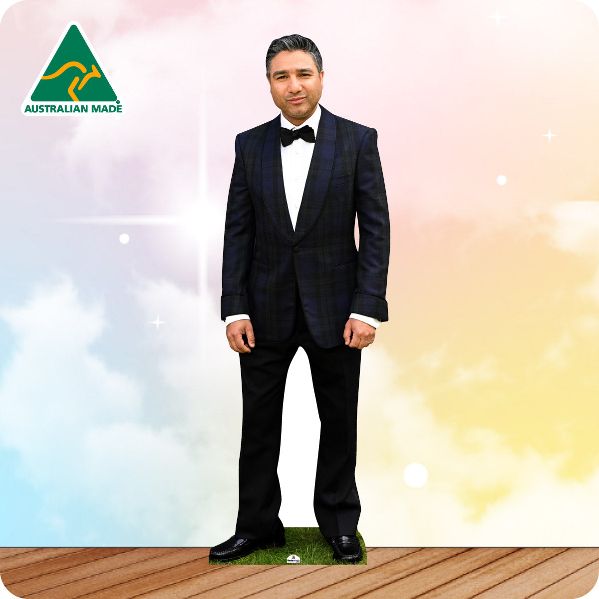 Man in a black suit with bow tie standing on grass with a colorful background and 'Australian Made' logo.