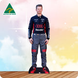Cardboard cutout of a person in a racing suit with visible branding on a wooden floor.
