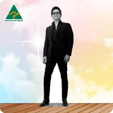 A man wearing a black suit, black shirt, black belt, and black sunglasses stands against a pastel sky background with clouds and a wooden floor. An 'AUSTRALIAN MADE' logo appears in the top-left corner.