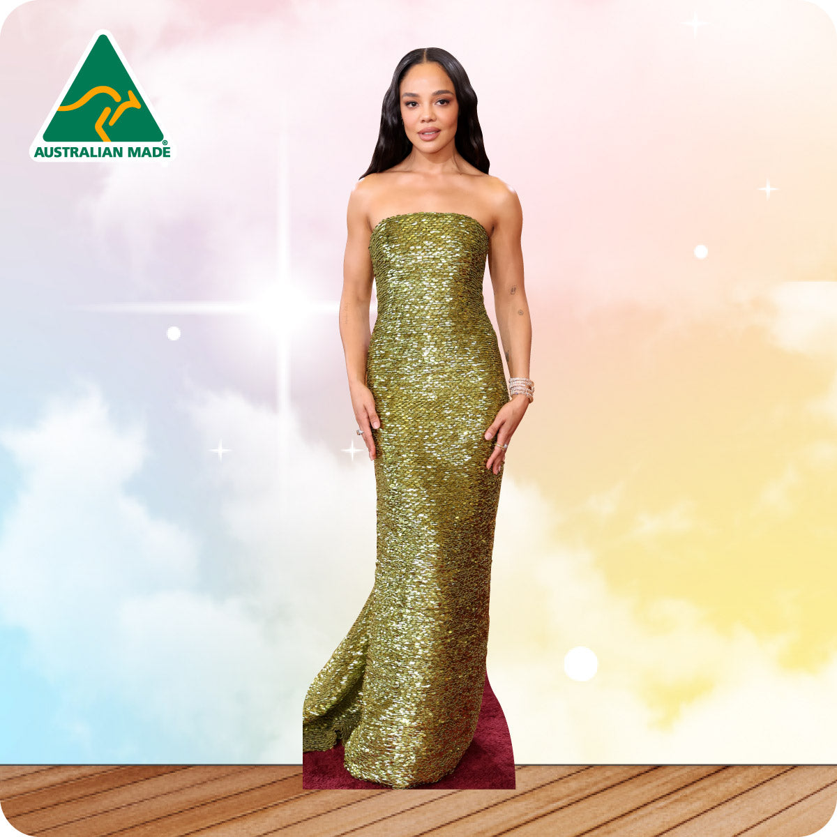 Woman in a gold strapless gown standing on a wooden floor with a colorful background
