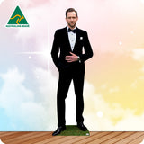 Cardboard cutout of a man in a black suit with a bow tie on a wooden floor.